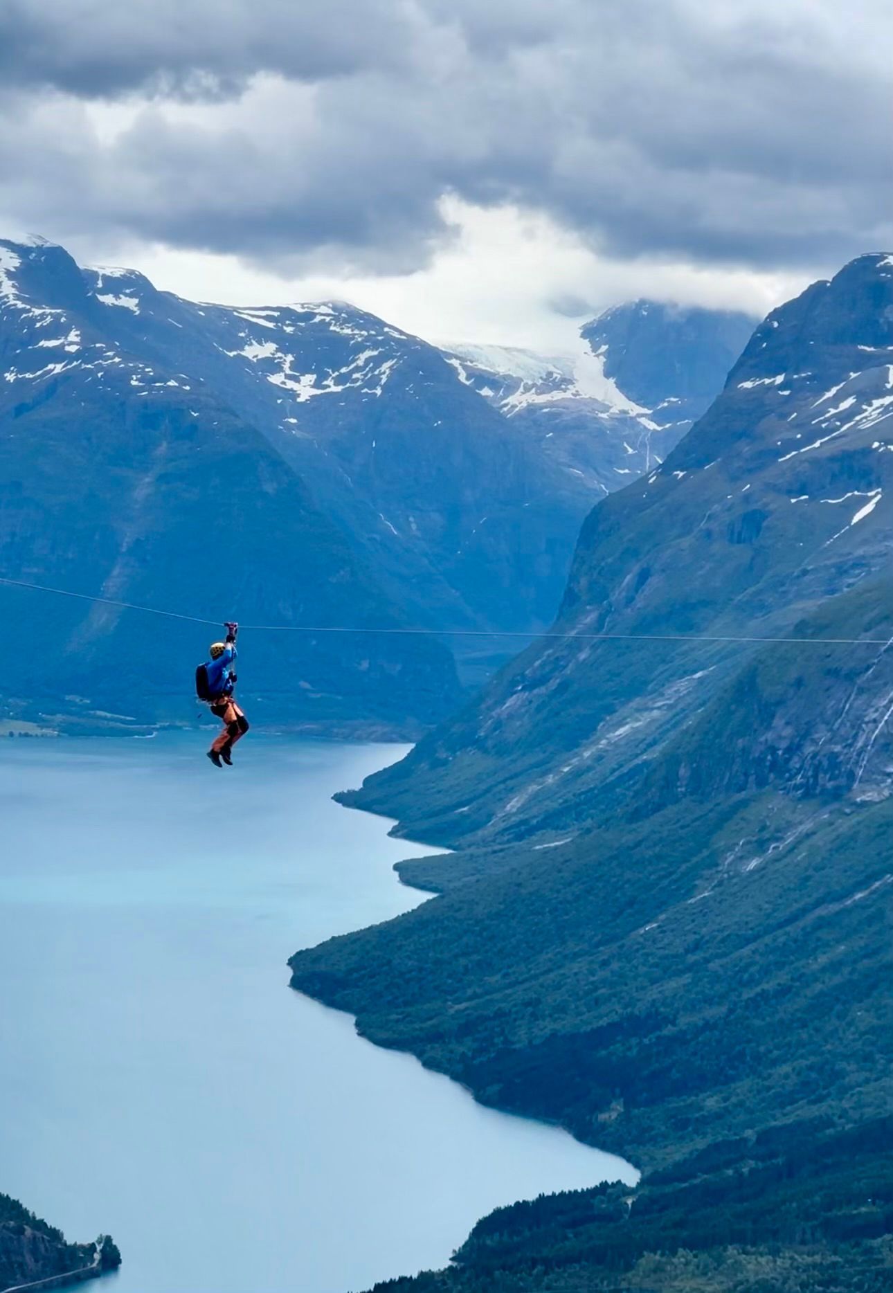 En person flyr over en innsjø med fjell i bakgrunnen