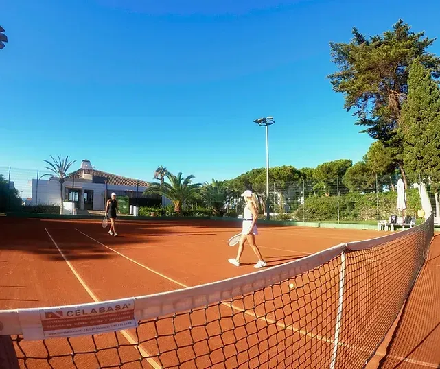 To personer spiller tennis på en leirbane