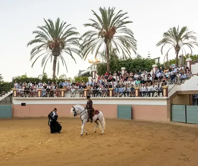En mann som rir på en hest foran en mengde mennesker