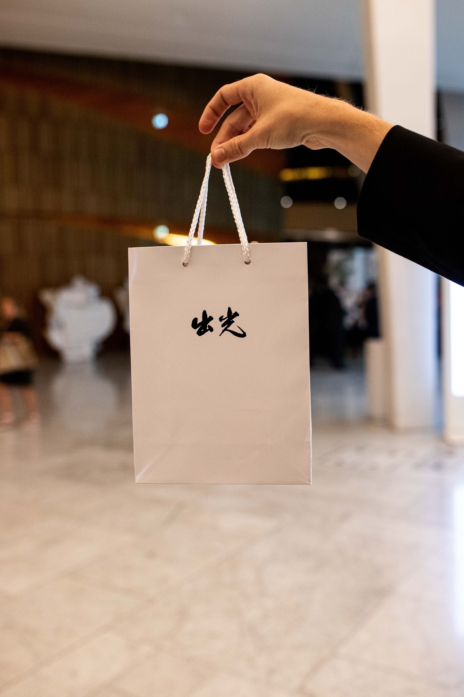 En person holder en hvit papirpose med kinesisk skrift på.