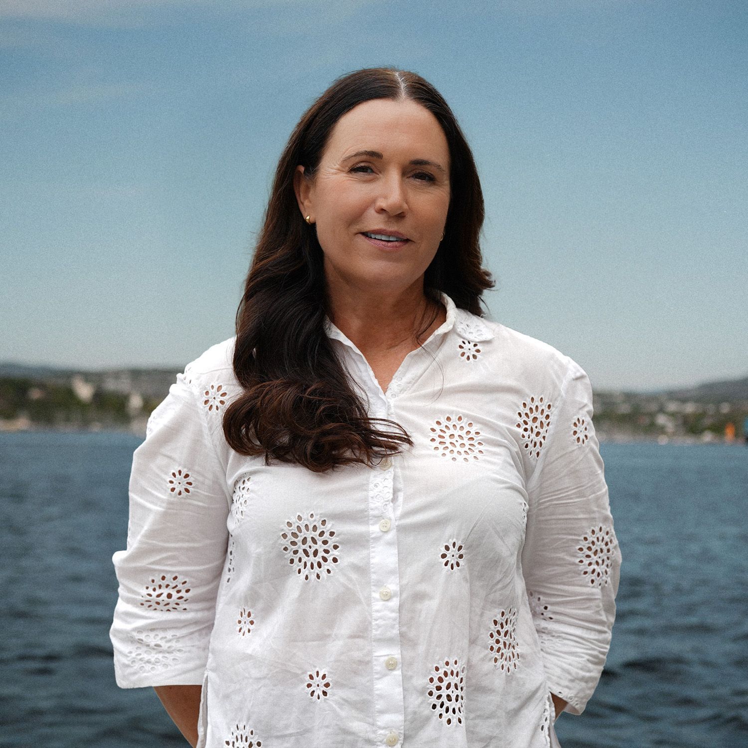 En mann med skjegg iført hvit skjorte står foran en vannmasse.
