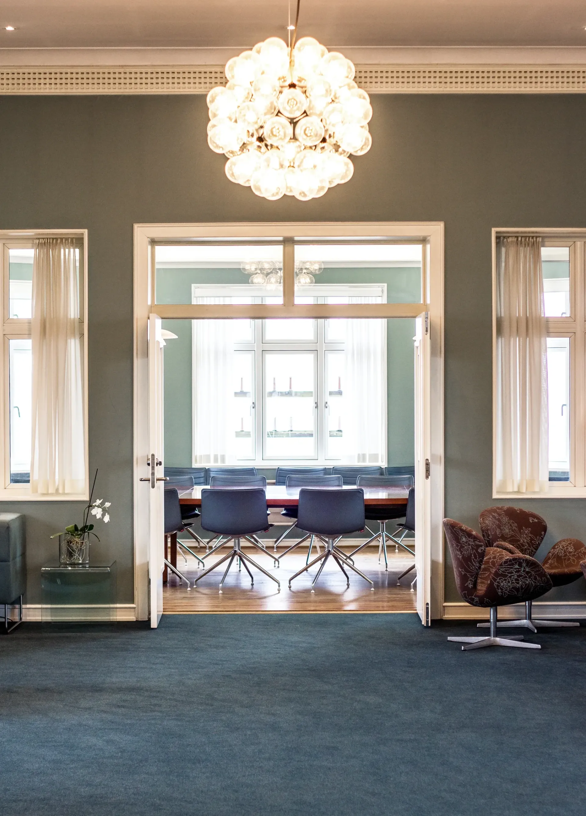 Et rom med bord og stoler og en lysekrone hengende fra taket