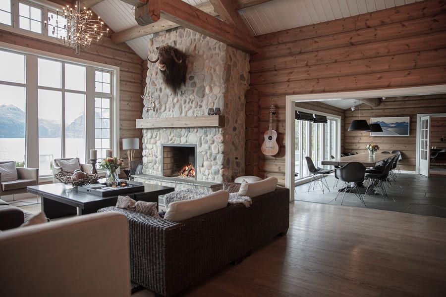 En stue fylt med møbler og en peis i en tømmerhytte.