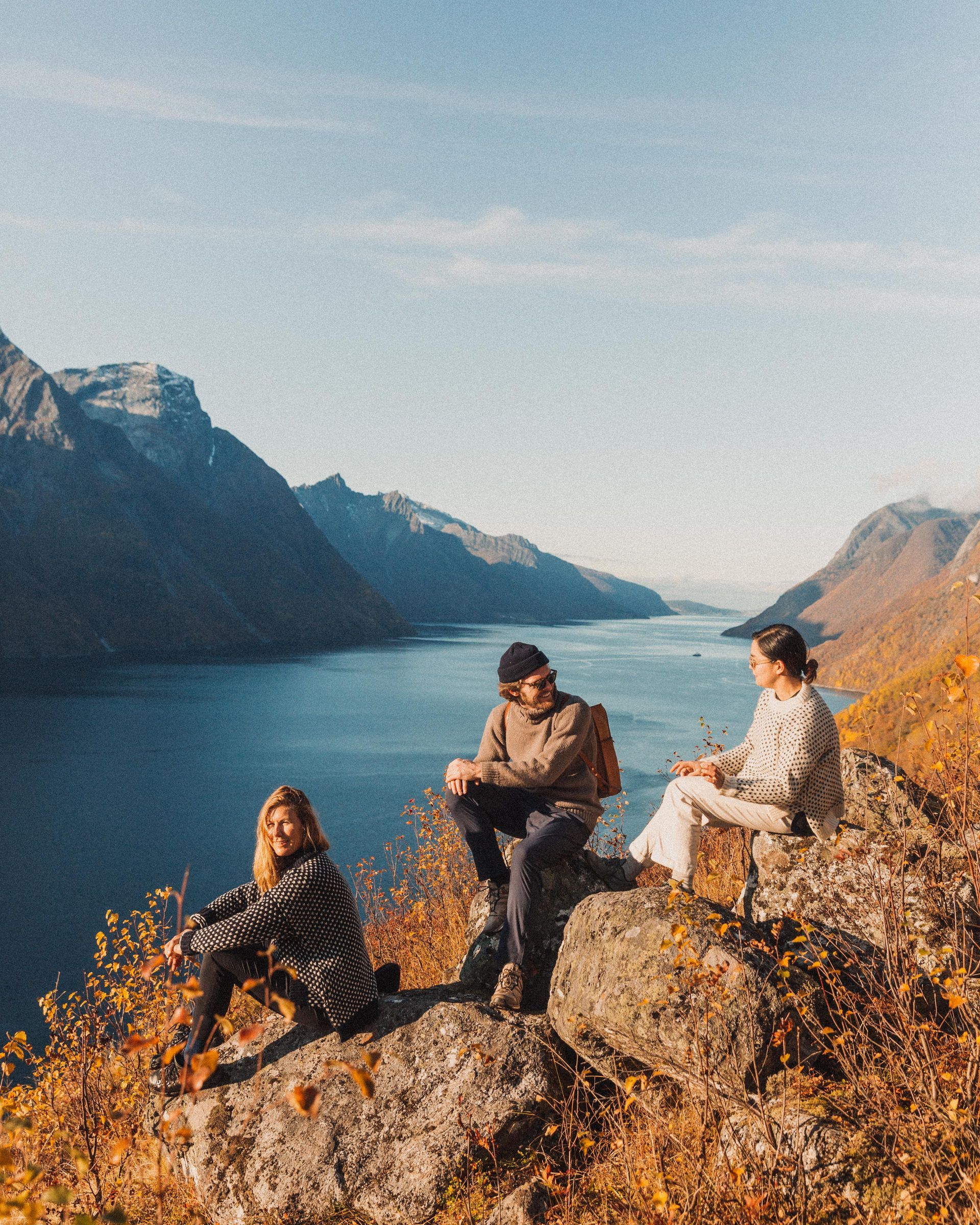 En person holder et glass iste foran en bysilhuett ved solnedgang.