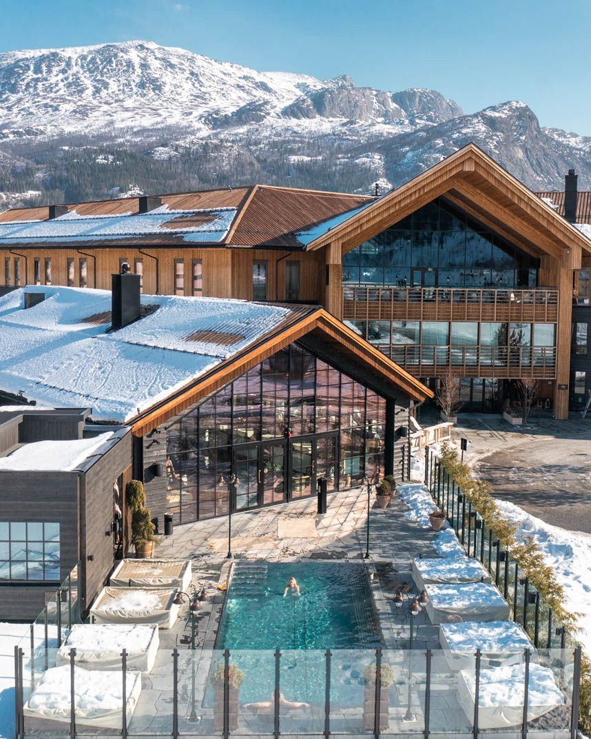 En person holder et glass iste foran en bysilhuett ved solnedgang.