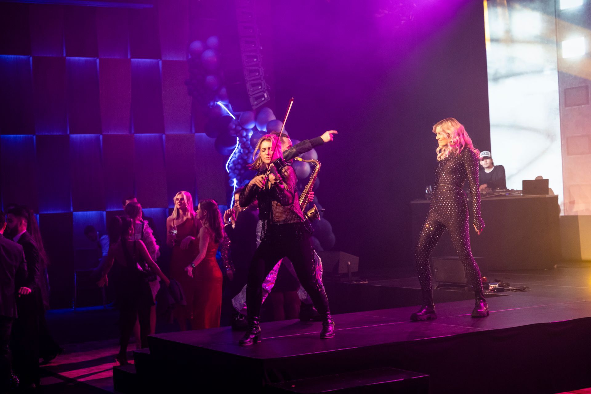 En gruppe mennesker danser og spiller fioliner på en scene.