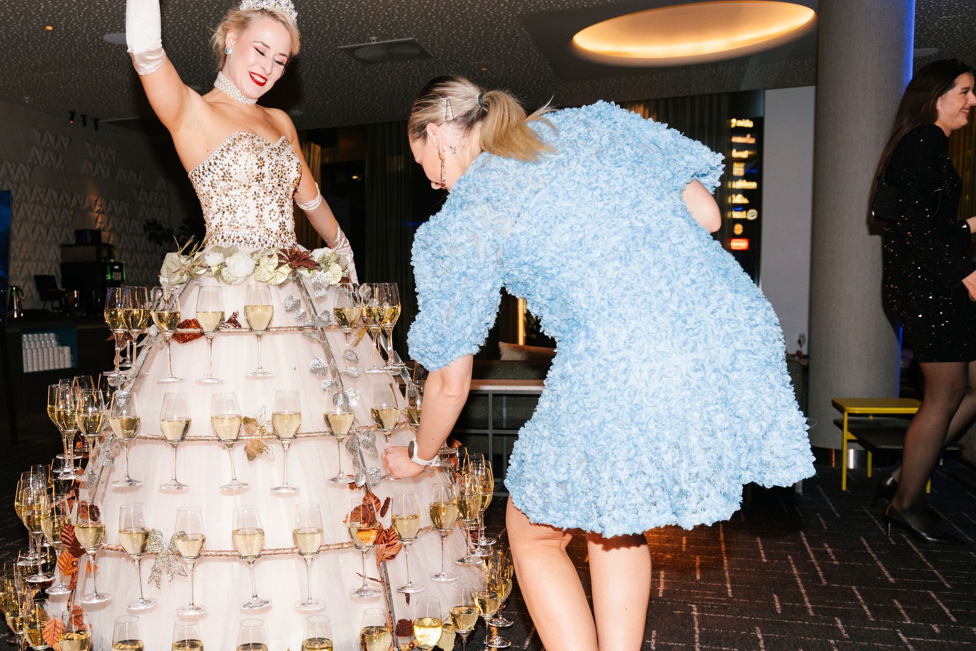 En kvinne i en blå kjole står ved siden av en kvinne i en hvit kjole