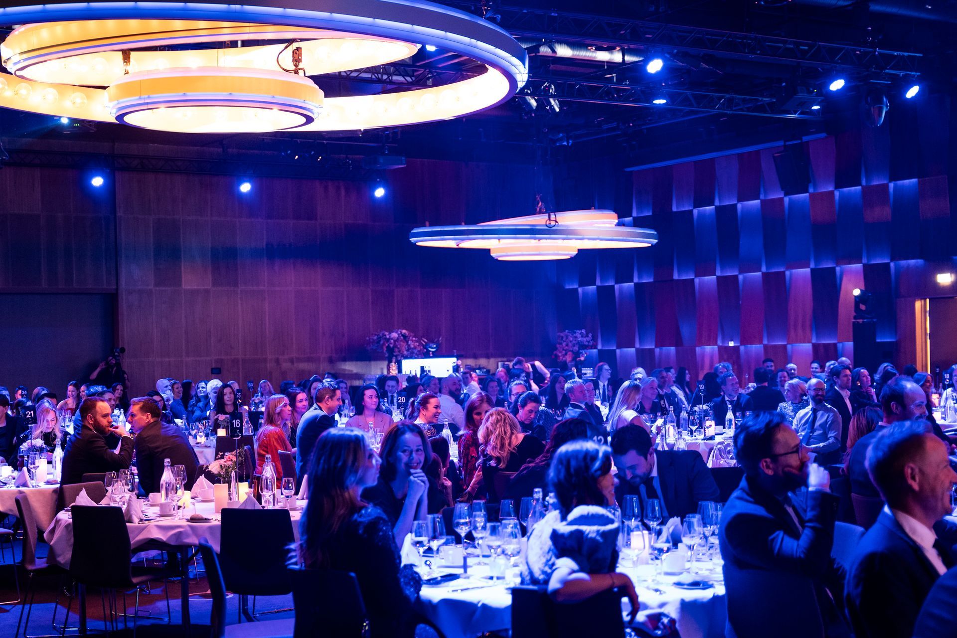 En stor gruppe mennesker sitter ved bordene i et stort rom.