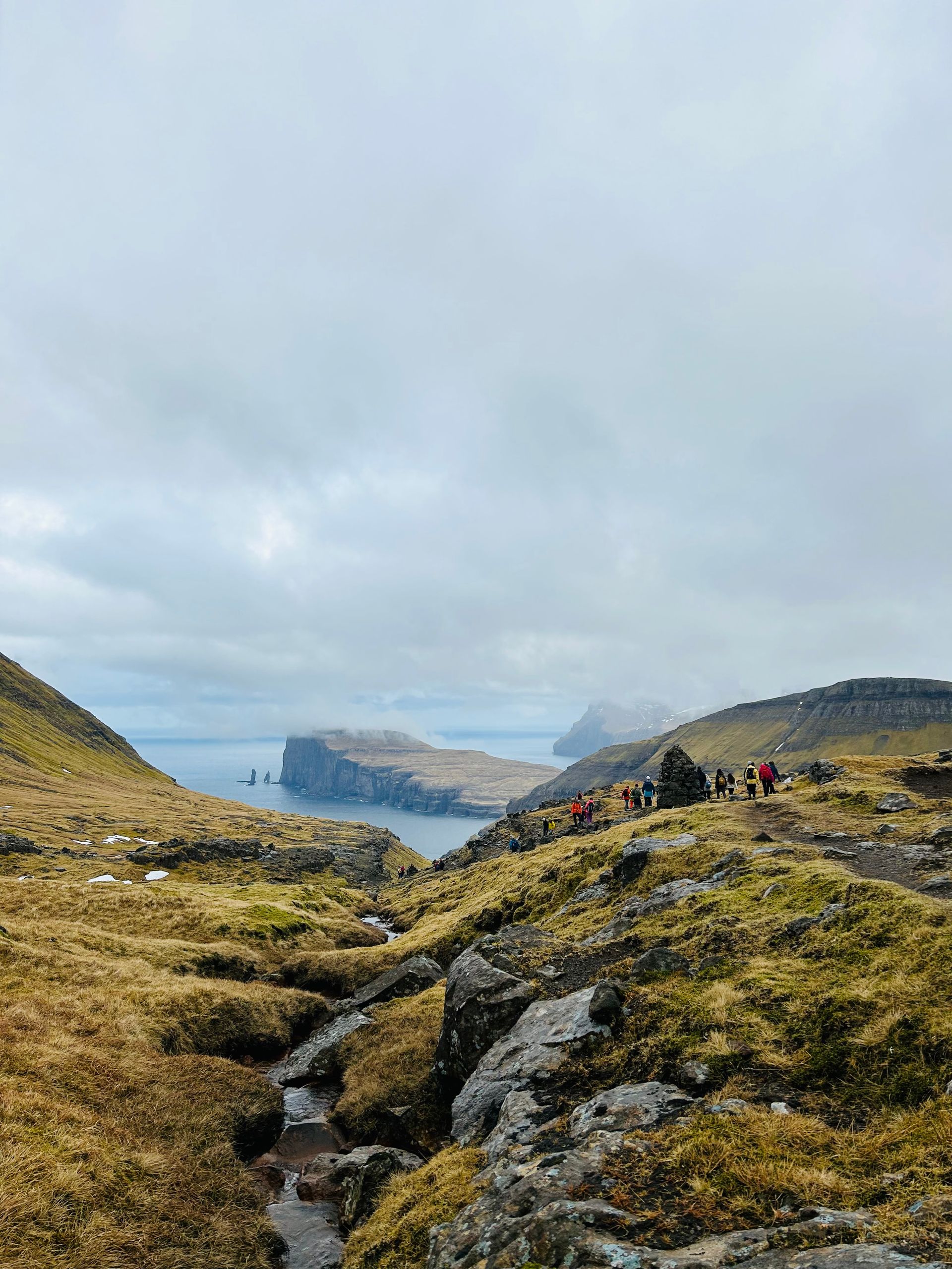 En gruppe mennesker står på toppen av en høyde med utsikt over en vannmasse.