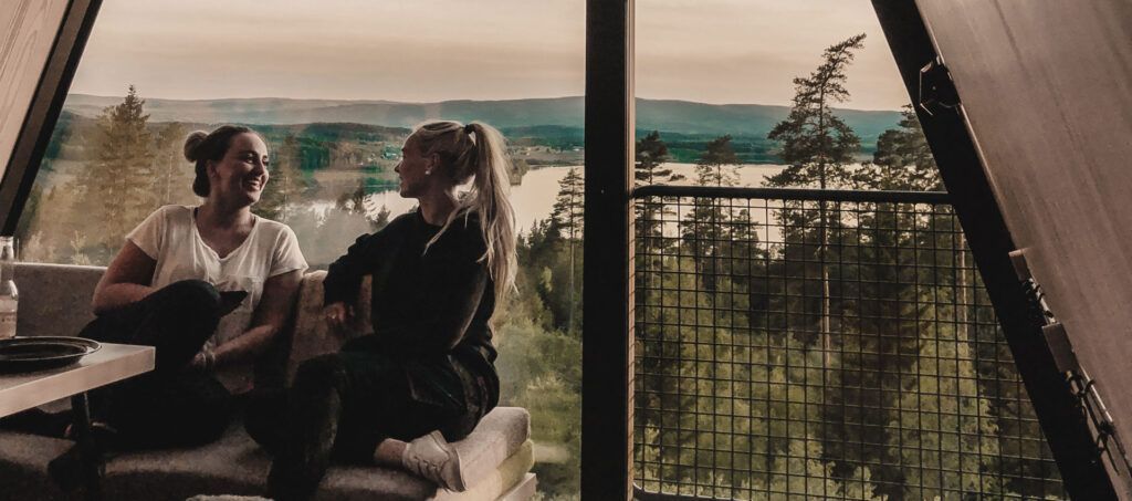 To kvinner sitter på en sofa og ser ut av vinduet.