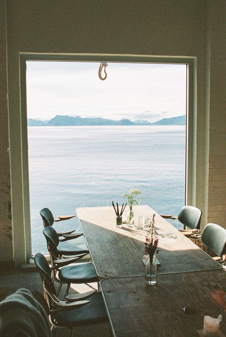 Et bord og stoler foran et vindu med utsikt over havet