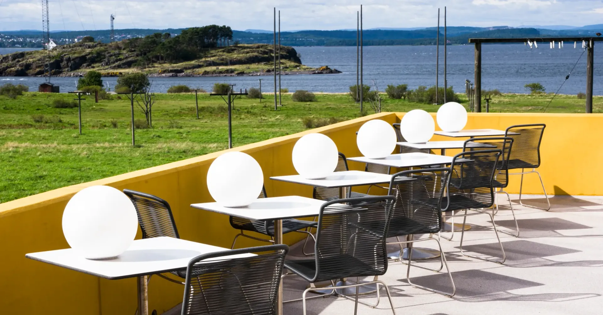 En rad med bord og stoler med utsikt over havet
