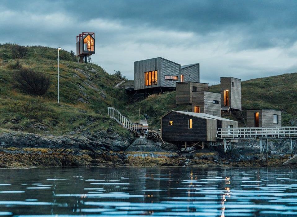 En gruppe hus som sitter på toppen av en høyde ved siden av en vannmasse.