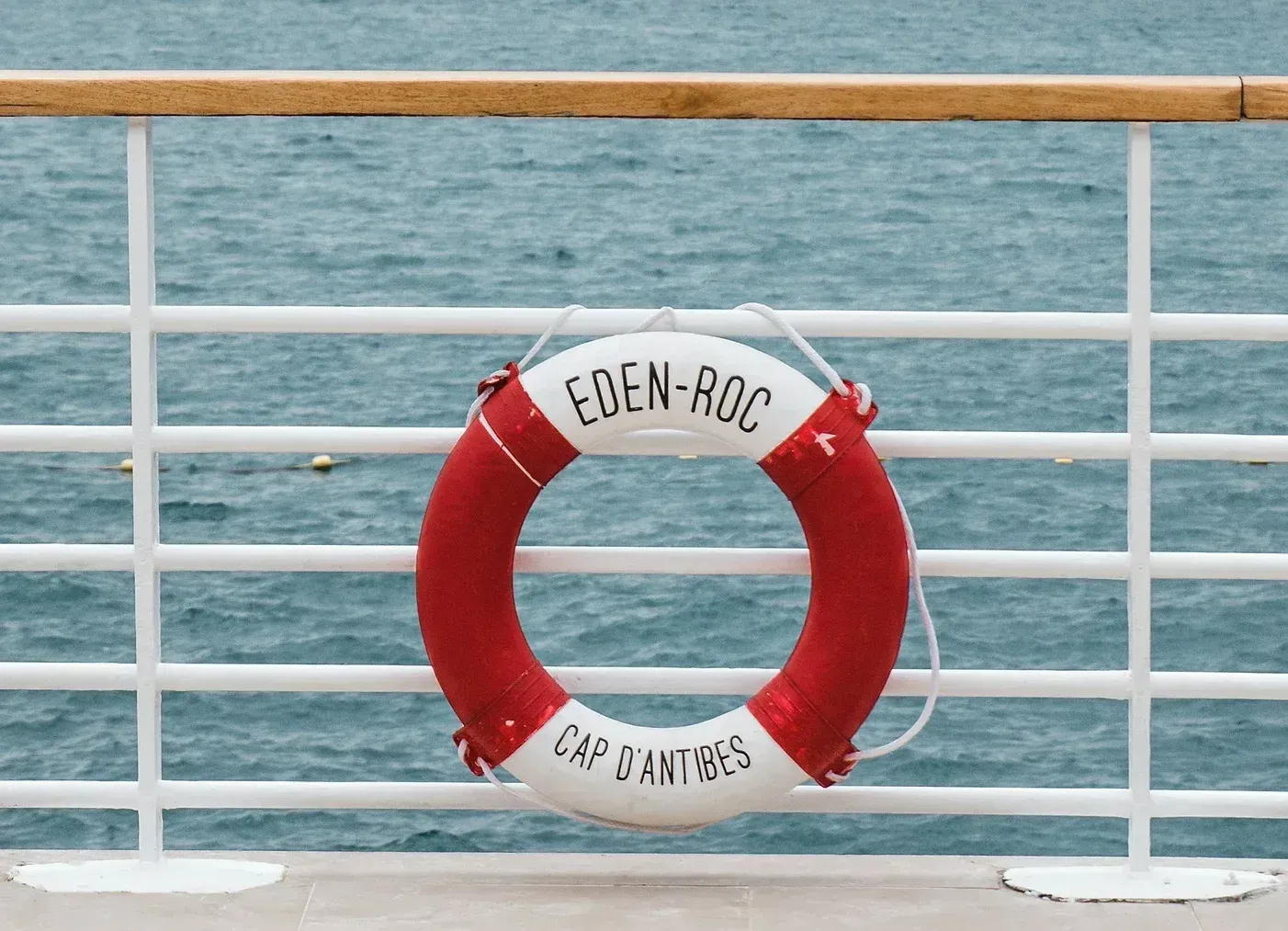 En rød og hvit redningsmann henger på et rekkverk med utsikt over havet.