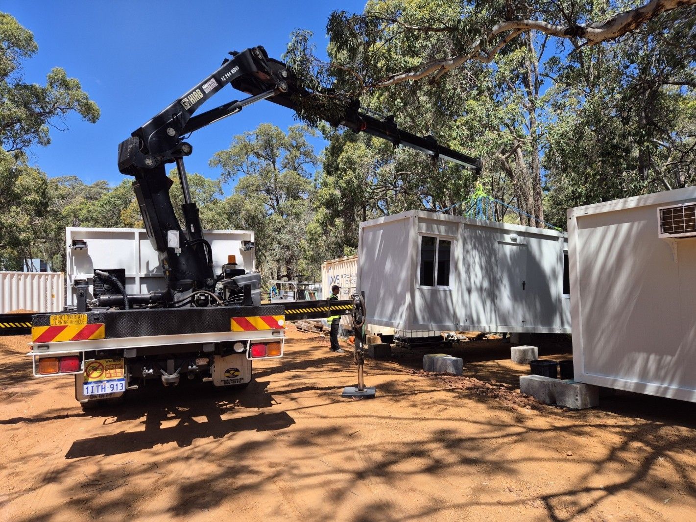 A tractor on a flatbed truck in a grassy field under a cloudy sky.