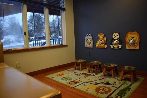 Waiting area with child-sized animal chairs, a small bench, and a colorful rug by a window