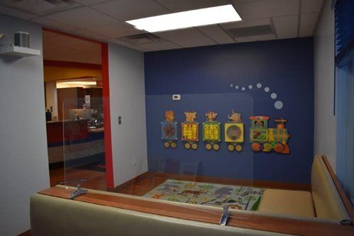Hallway play area with colorful wall murals and a small play table under ceiling lights