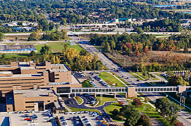Aerial view of a large office campus with parking lots, roads, and trees in the background