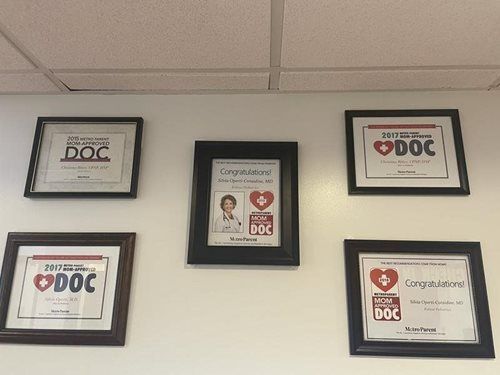 Three framed DOC certificates and an employee recognition plaque on a wall.