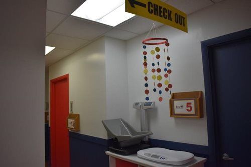 Hospital check-out area with red and blue doors, a counter, and a hanging mobile decoration.