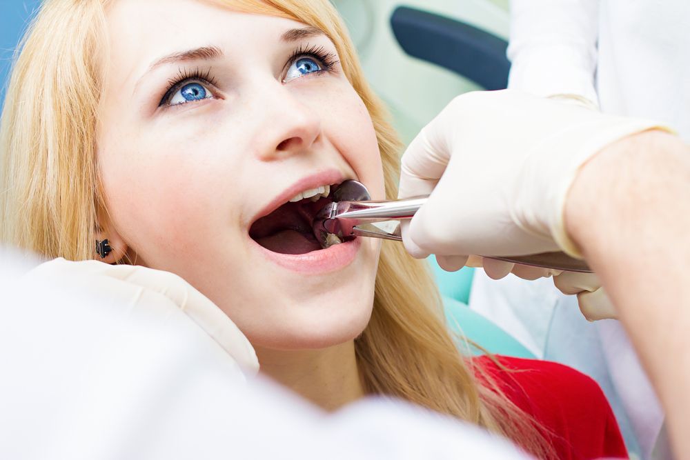 Dentist in White Gloves Using Dental Forceps — Killara Dental in East Killara, NSW