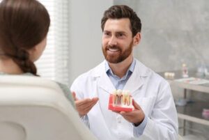 A Dentist in a White Coat Smiles While Explaining a Dental Model — Killara Dental in East Killara, NSW