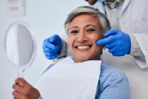 A Dental Patient Smiling While Holding a Hand Mirror as a Professional — Killara Dental in East Killara, NSW