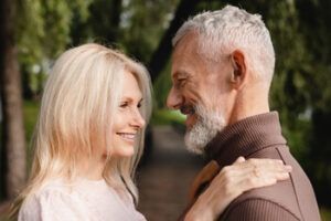 A Couple Looks Into Each Other’s Eyes With Smiles While Standing in a Park Setting — Killara Dental in East Killara, NSW