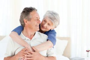 A Smiling Couple Embraces Affectionately in a Bright, Light-filled Bedroom — Killara Dental in East Killara, NSW