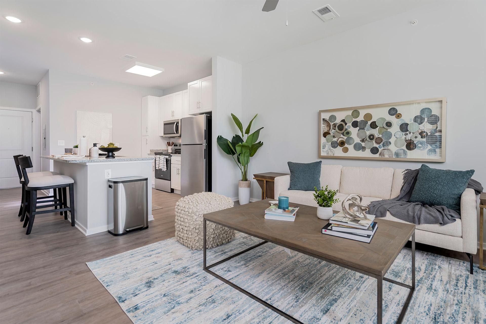 A modern living room with a kitchen in the background.