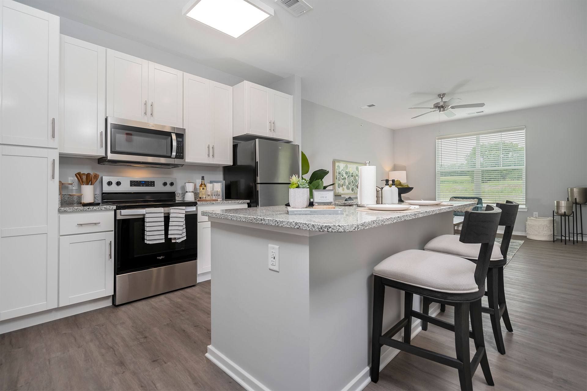 A kitchen with a white island and black bar stools.