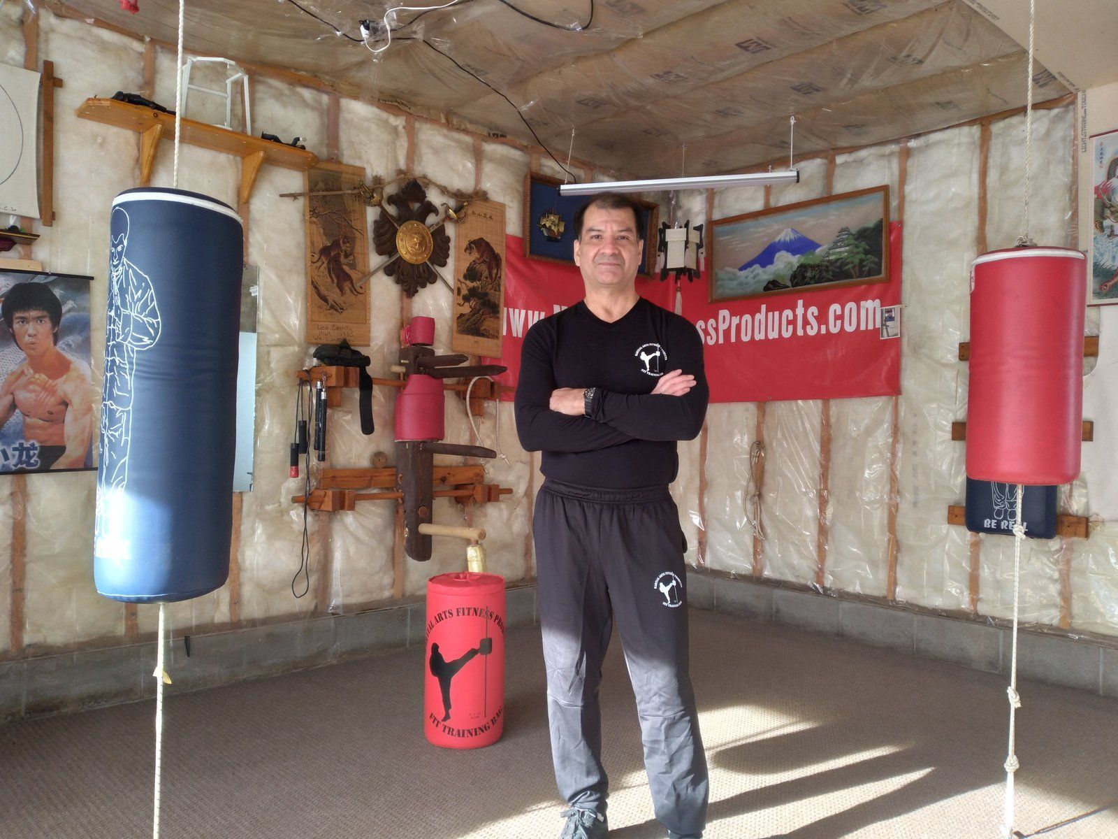 A man is standing in a room with a sign that says ' martial arts.com ' on it