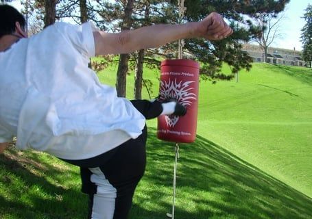 A man is practicing martial arts kicking a bag in field