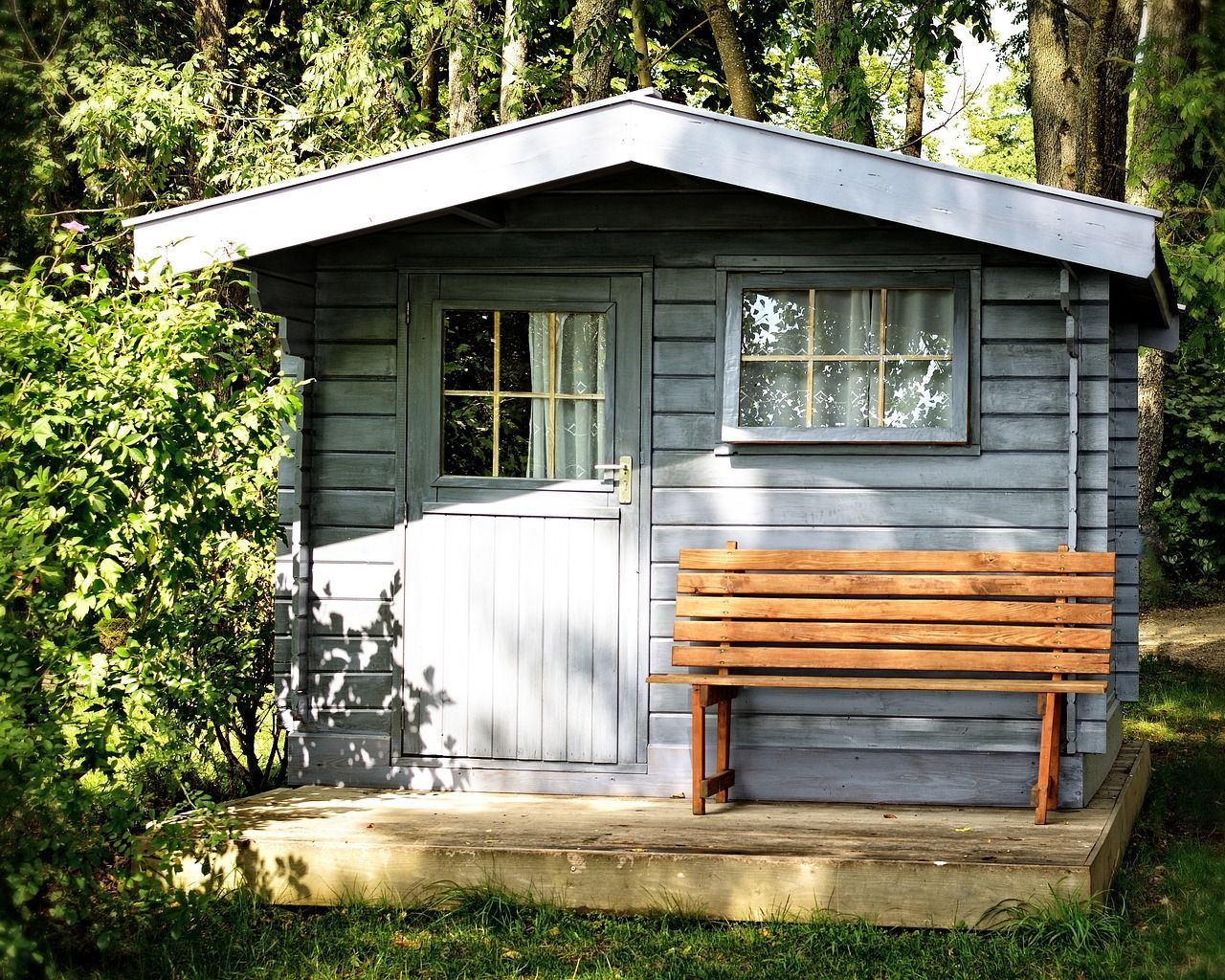 A soft blue-grey garden shed in a Reading home garden, expertly painted by Snowflake Decor.