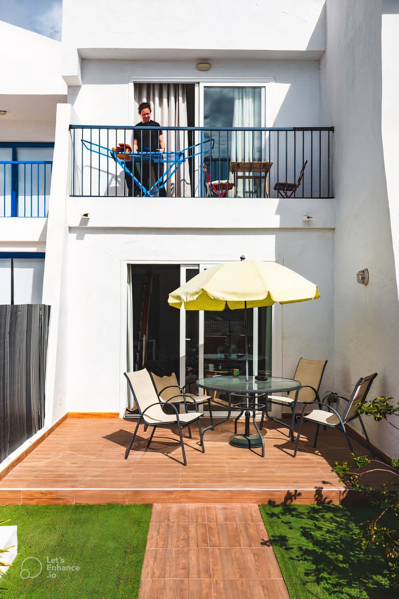 A man standing on a balcony with a yellow umbrella