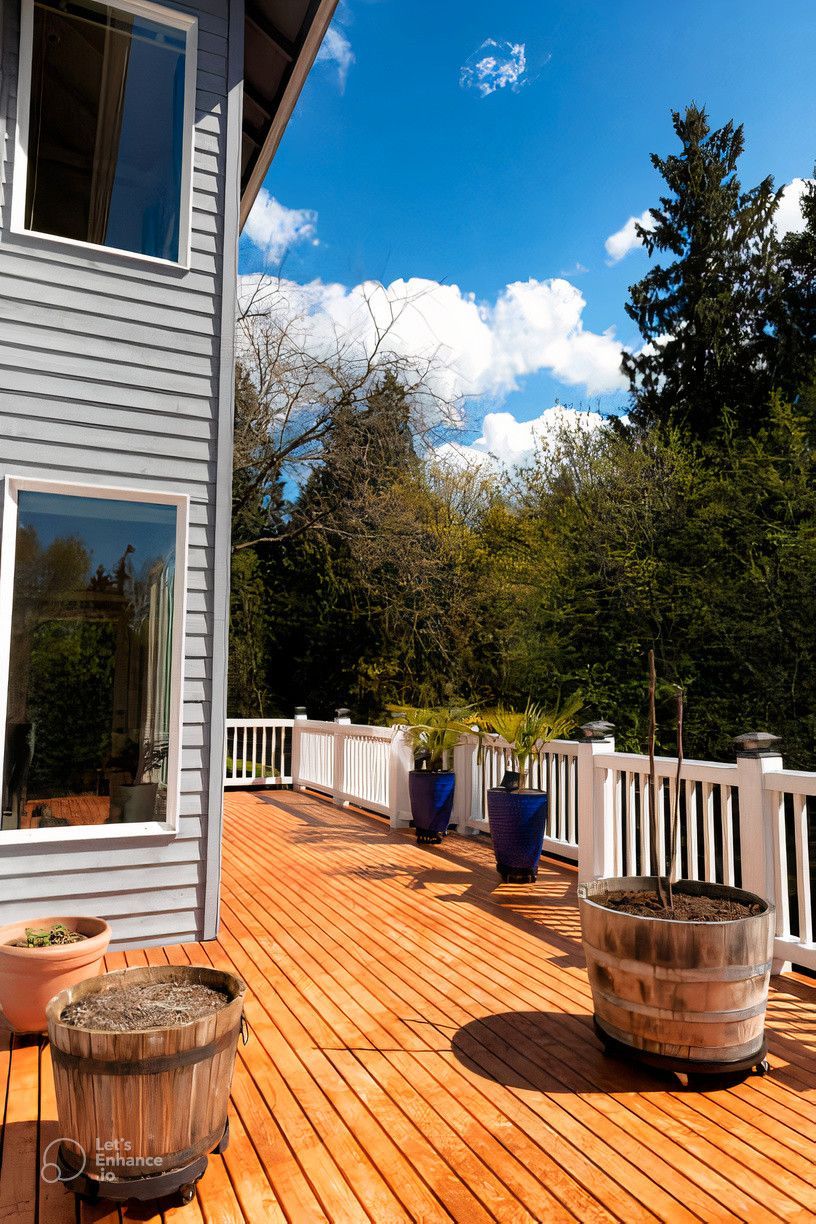 A wooden deck with potted plants on it in front of a house.