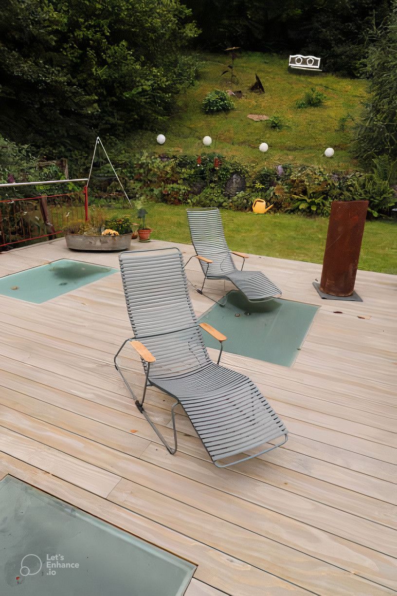 Two lounge chairs are sitting on a wooden deck.