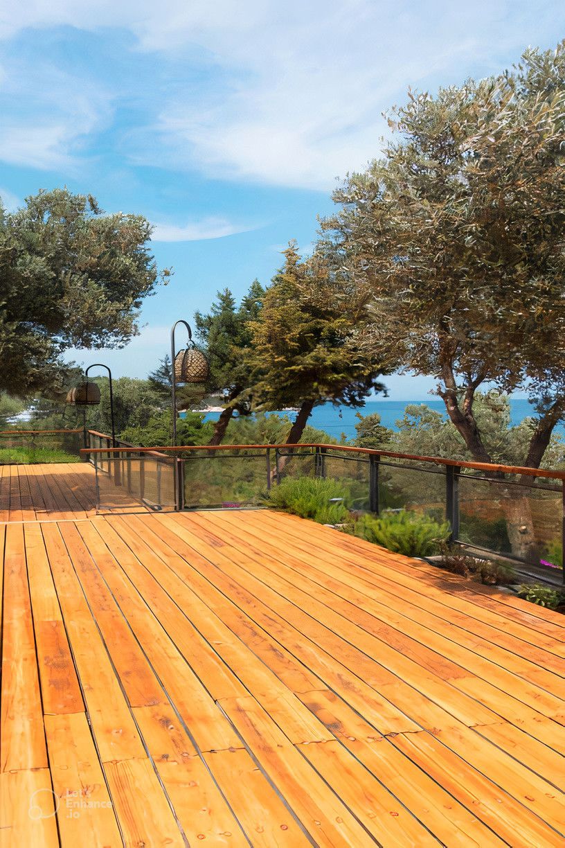 A wooden deck with a view of the ocean and trees.