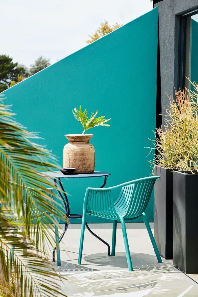 A backyard with green painted fence and cahir