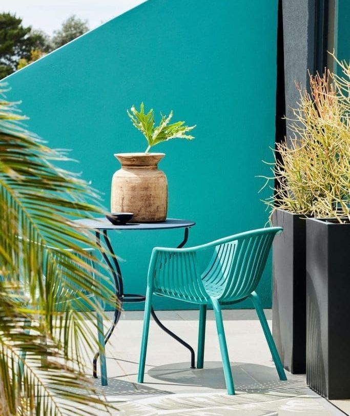 A backyard with green painted fence and cahir