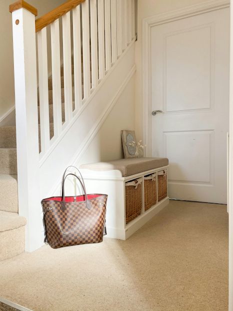 A brown louis vuitton bag is sitting on a bench under a staircase. Staircase expertly painted by Snowflake Decor in Reading, UK.