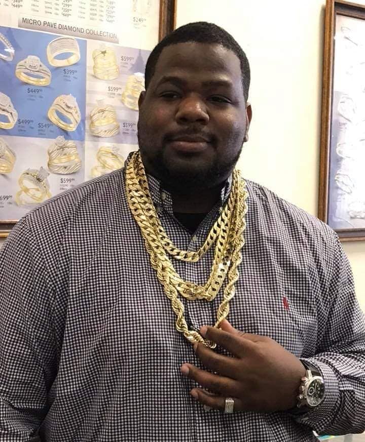 Man wearing multiple gold chains and a watch, in a jewelry store.