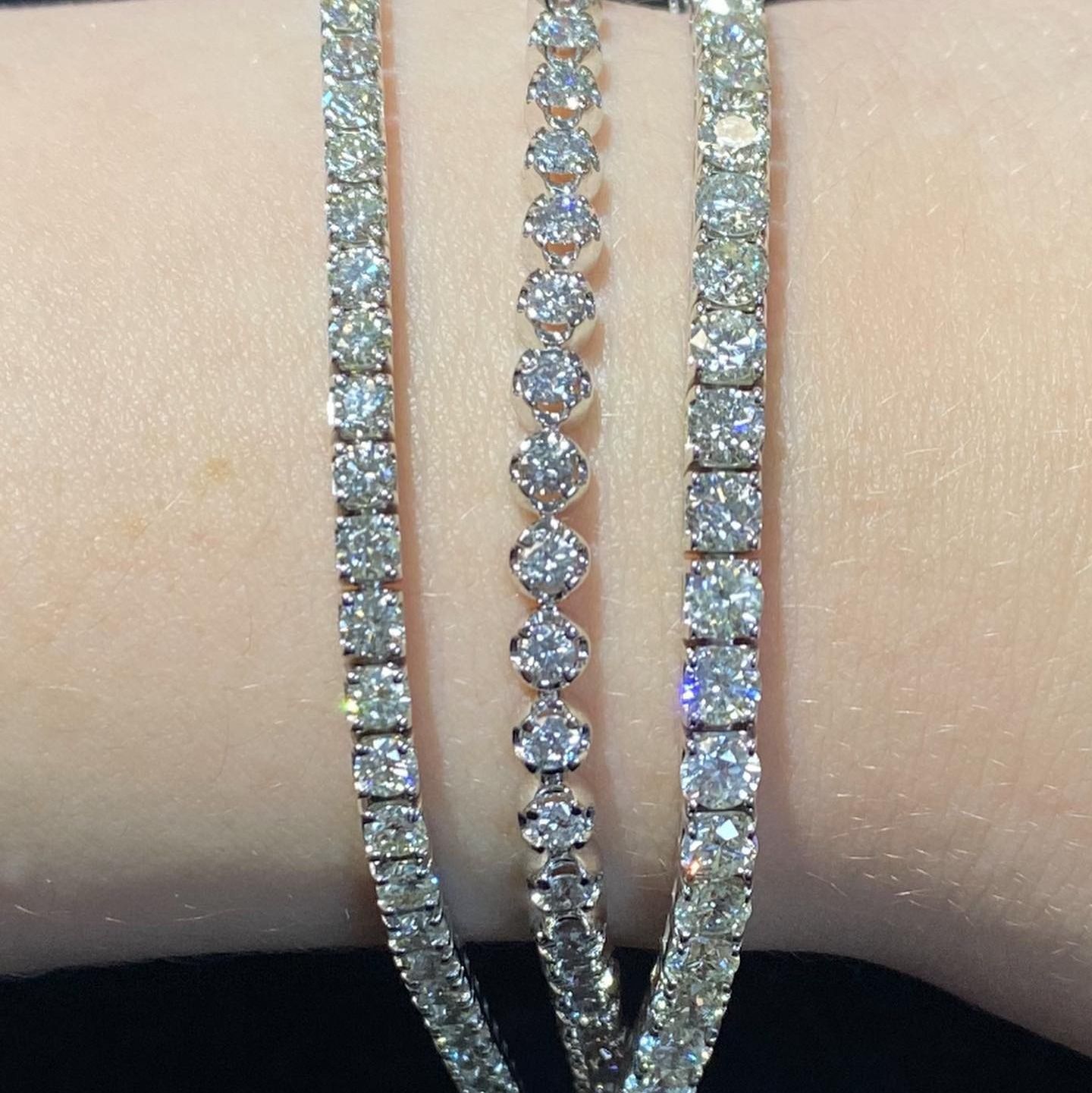 Three diamond bracelets on a wrist, sparkling against skin.