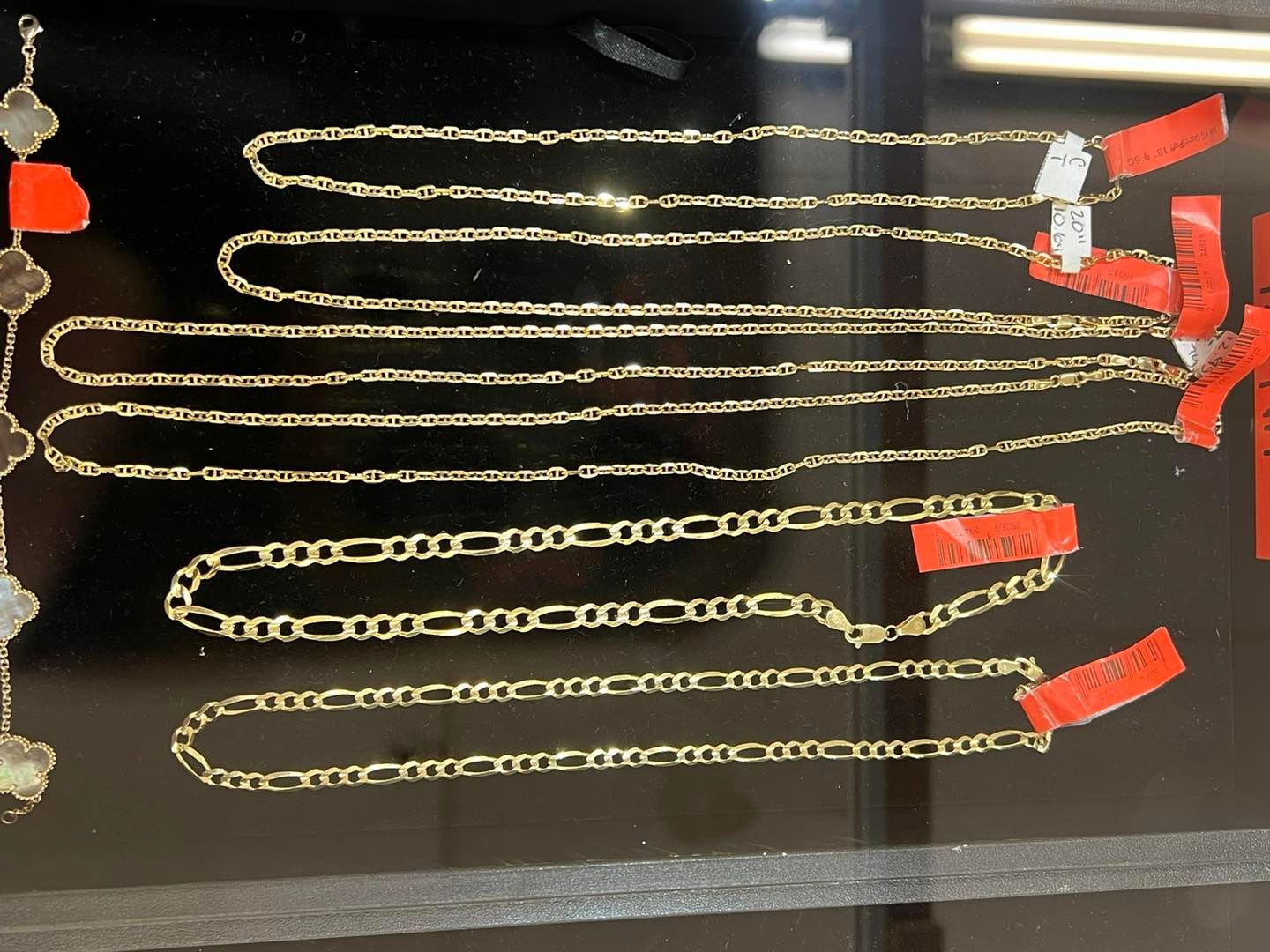 Gold necklaces displayed on a dark surface, with red price tags attached.