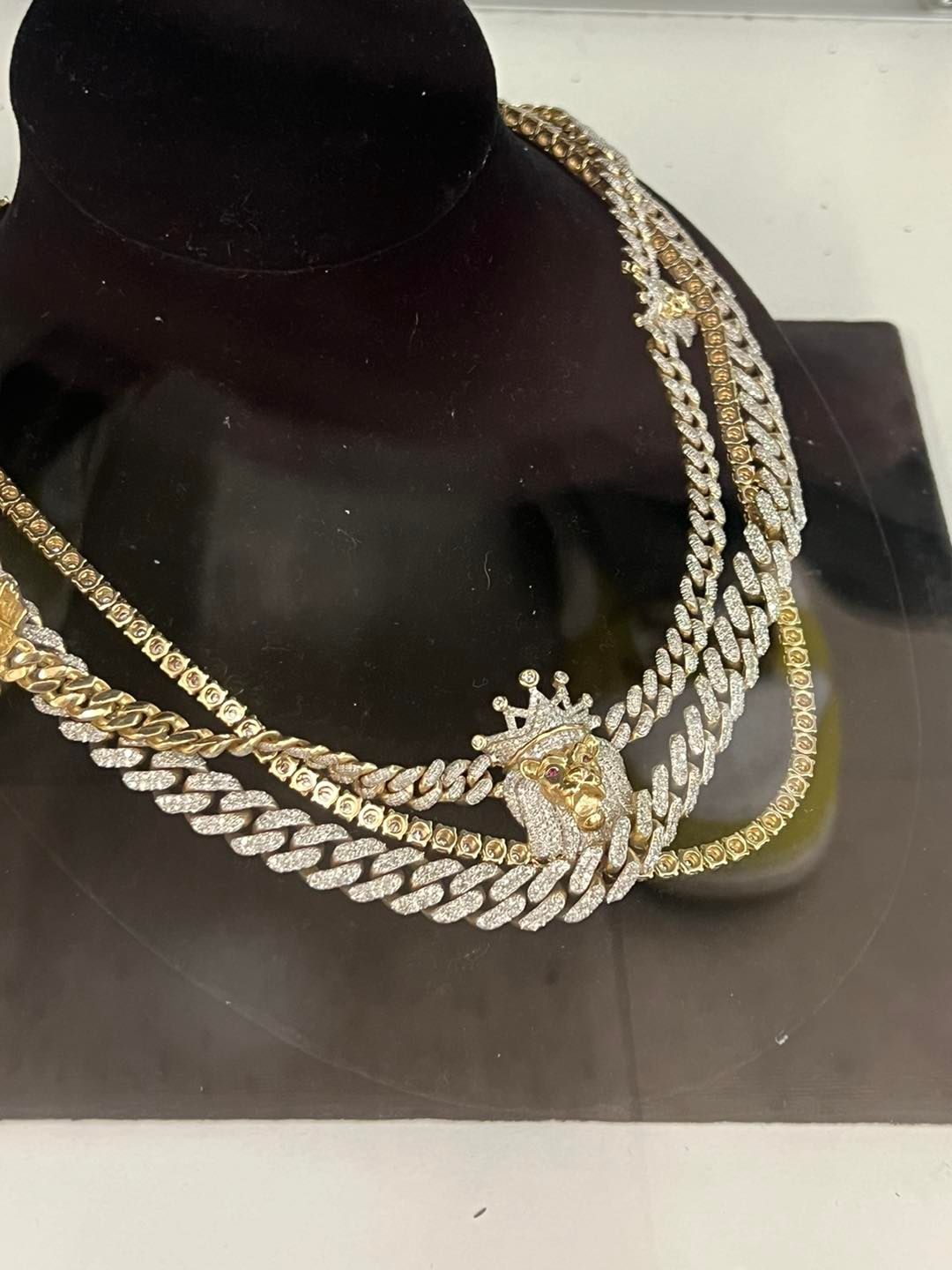 Gold and diamond necklaces displayed on a black stand with a crown pendant.