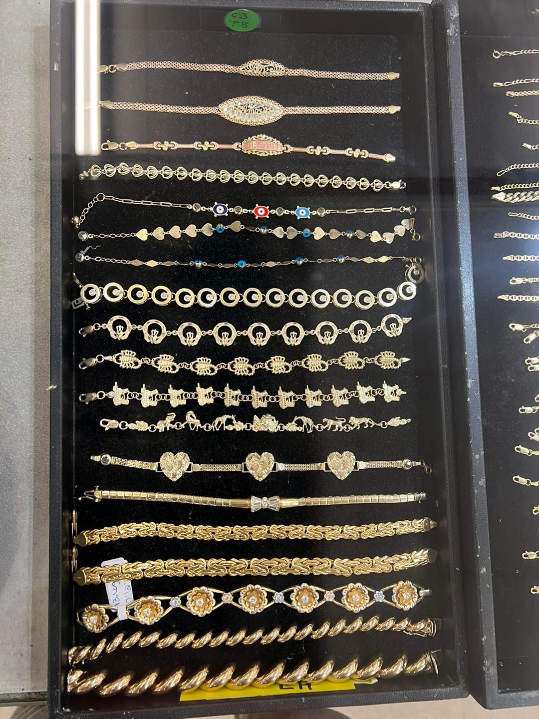 Display case with rows of gold bracelets, various styles and designs.