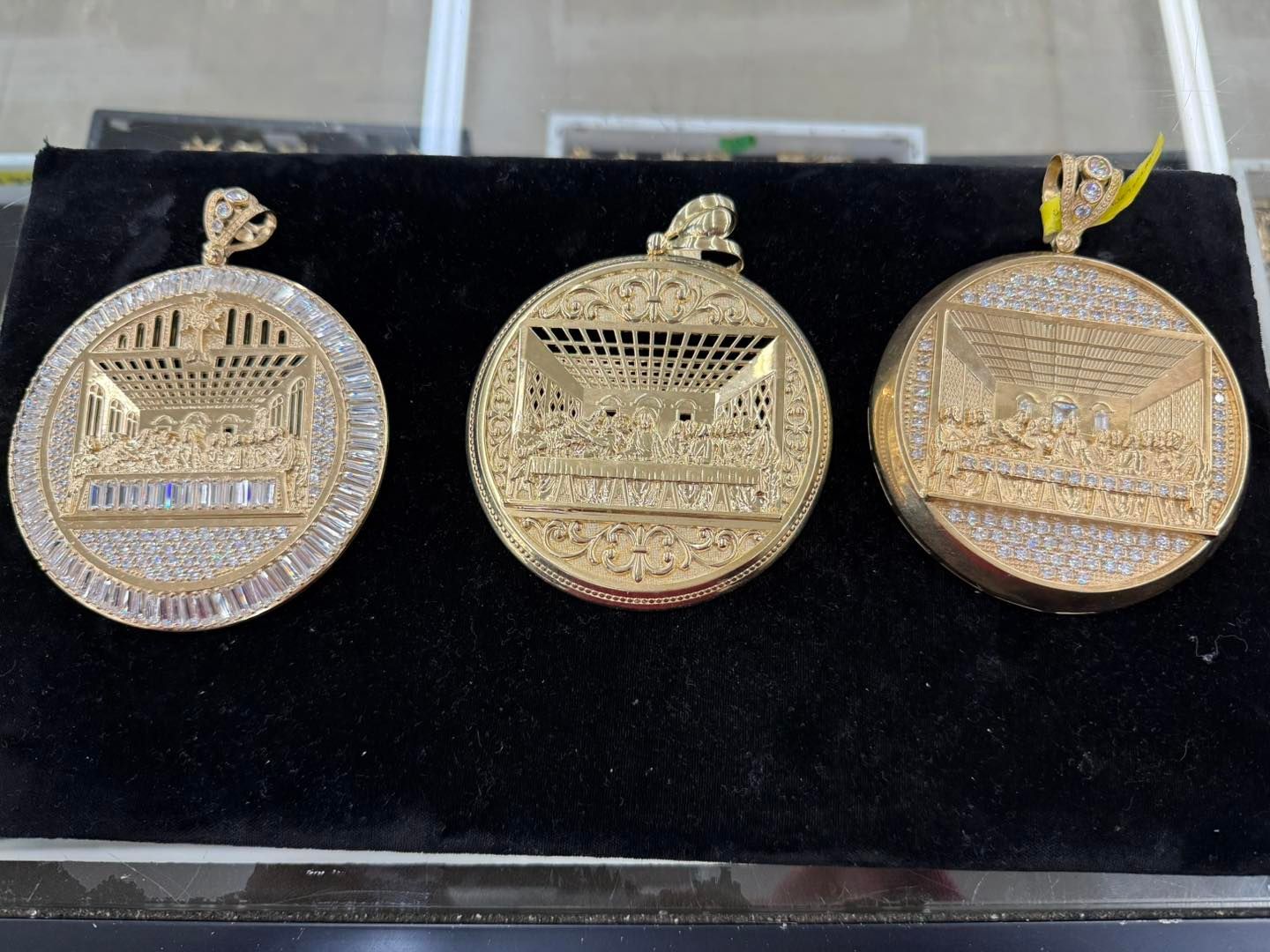 Three gold pendants with diamond detailing depicting the Last Supper scene.