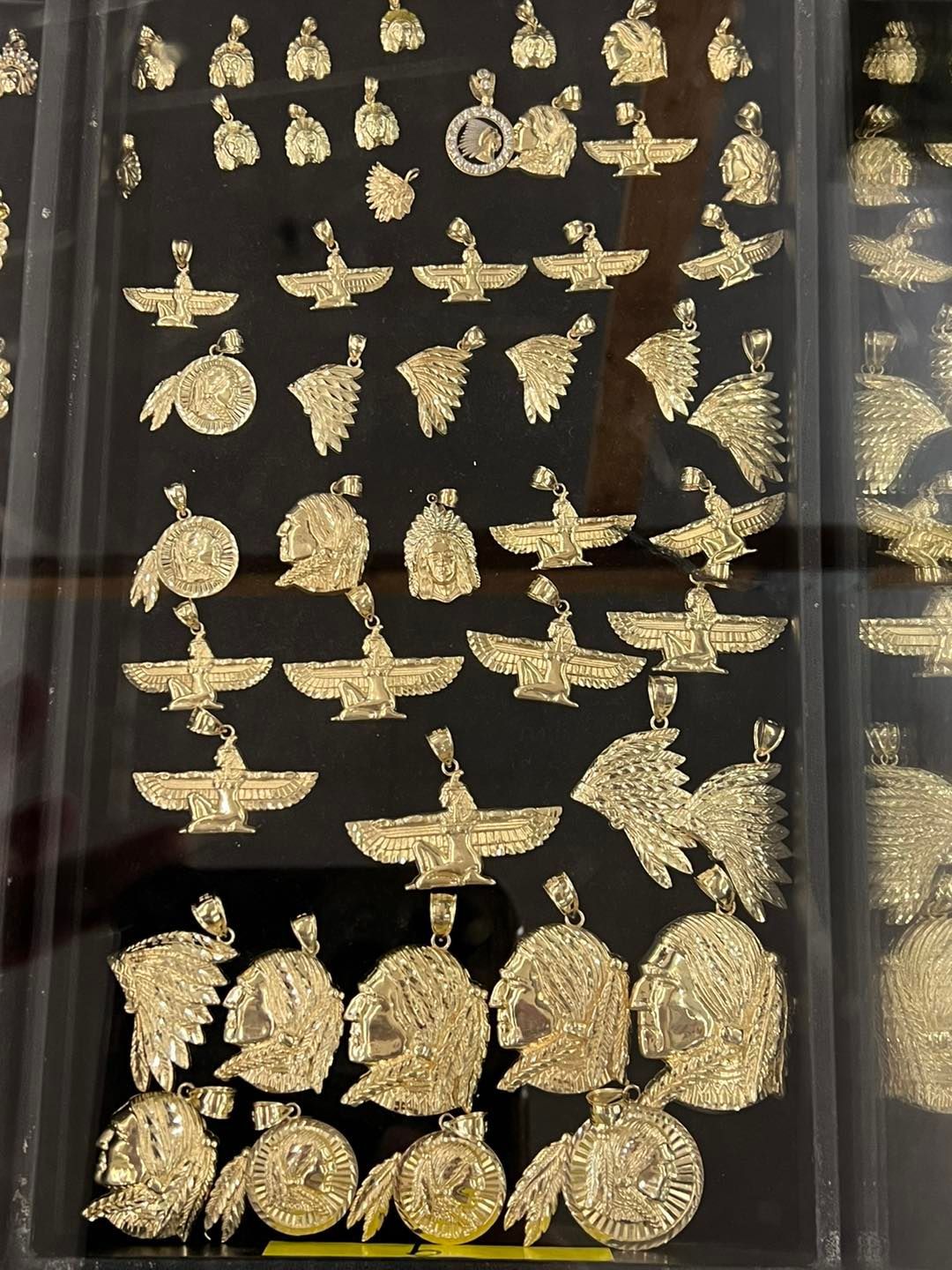 Gold pendants arranged on a black display, featuring various designs like eagles and Native American imagery.