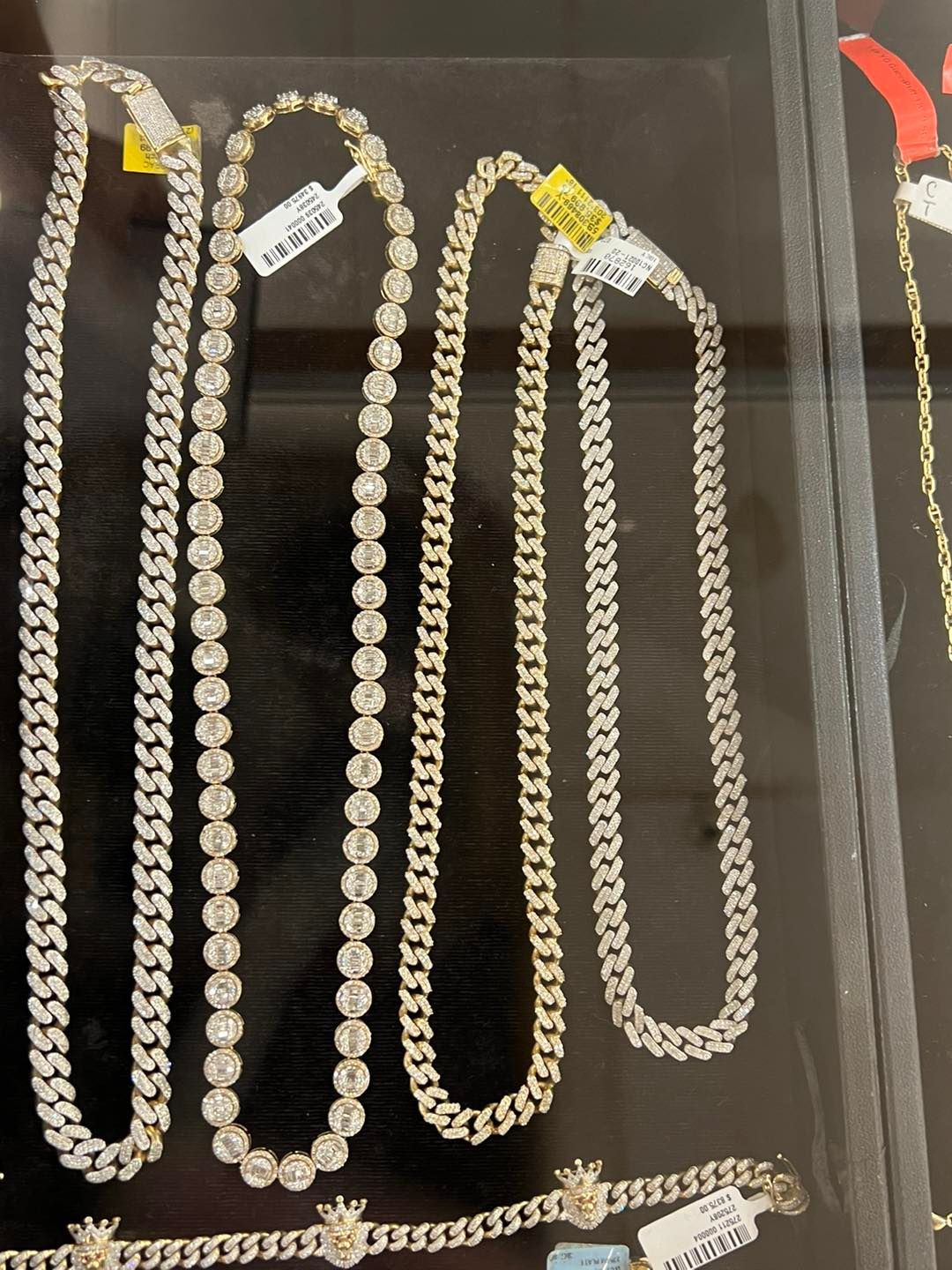 Jewelry display: Various diamond and gold necklaces on black background.