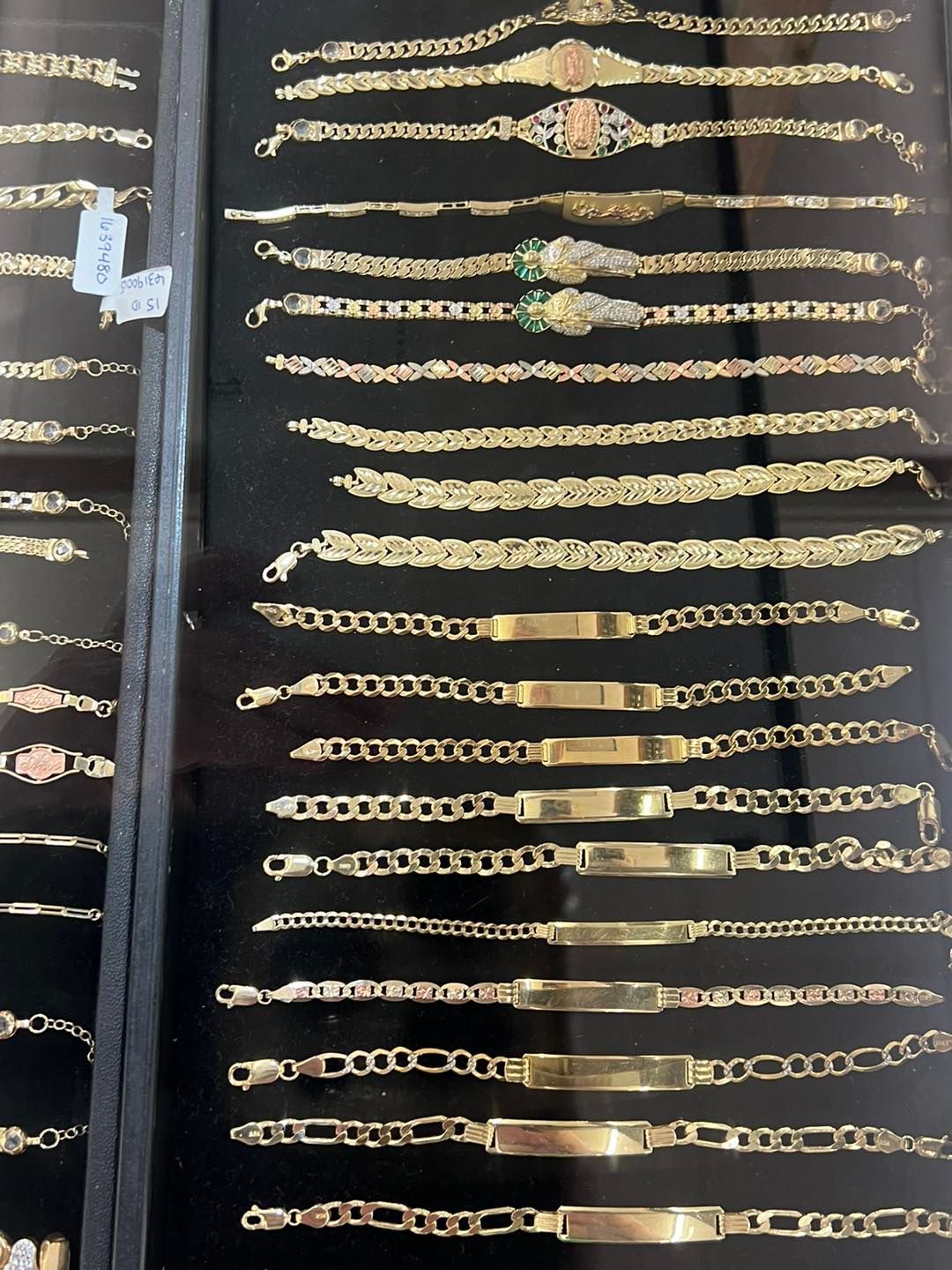 Display case of gold bracelets with various styles and designs.